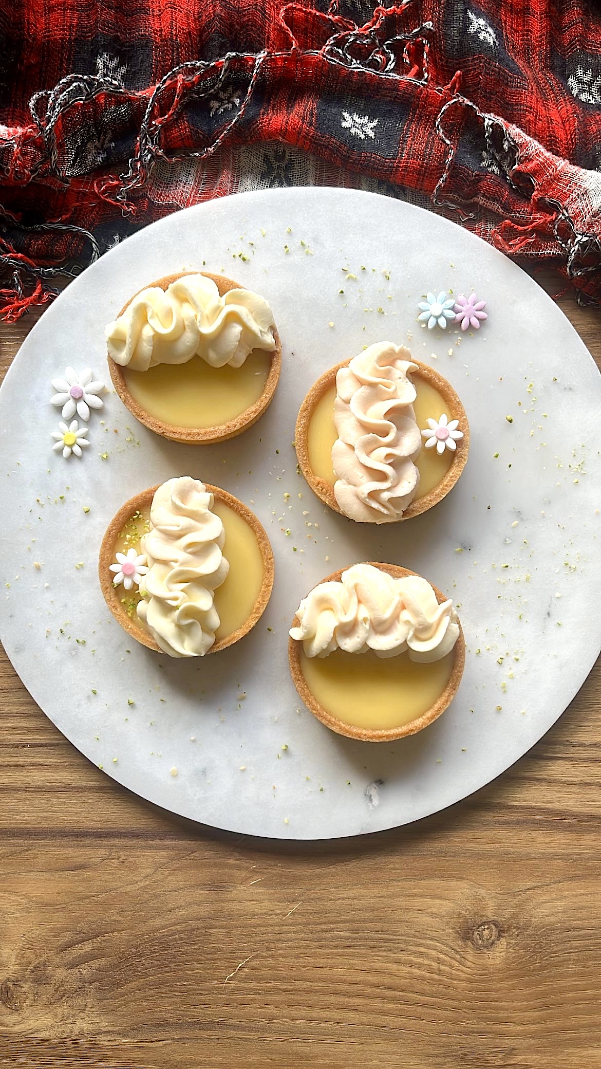 Four lemon tarts decorated with wave-shaped cream on top